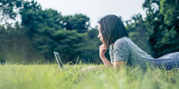 Student in grass on laptop